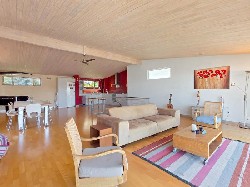 Spacious open-plan living and dining area featuring high timber ceilings, hardwood flooring, and a functional kitchen with built-in appliances.