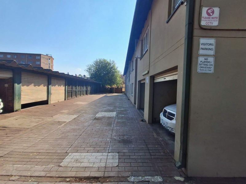 Exterior view of the townhouse complex driveway featuring a row of garages and paved access area.