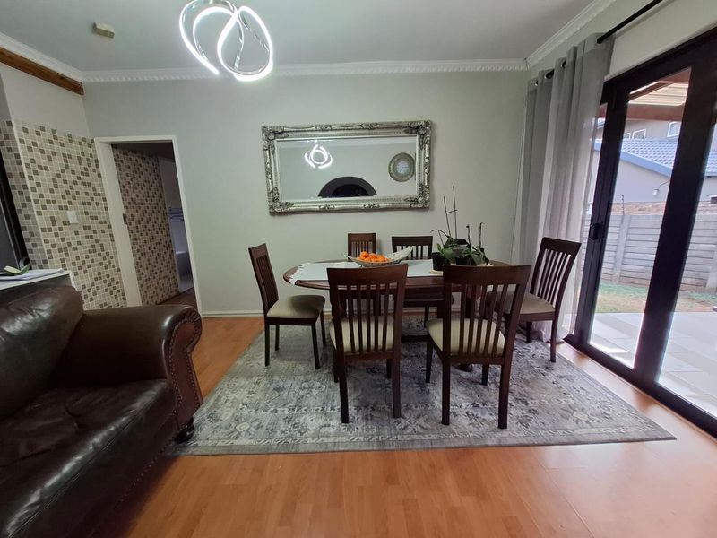 A well-lit dining area featuring laminate flooring, crown molding, and a sliding glass door providing access to the exterior.