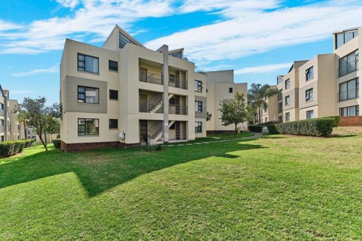 A view of the rear facade of the townhouse complex, featuring multi-level balconies, external staircases, and well-maintained communal lawn areas.