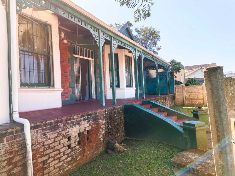Front elevation of a traditional townhouse featuring a covered veranda with decorative timber fretwork, brick facade, and tiled entrance steps.