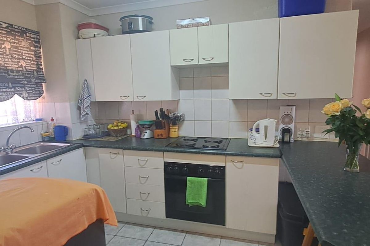 A functional kitchen featuring built-in cabinetry, a dark laminate countertop, a built-in oven, and a hob with a tiled splashback.