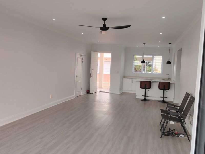 Spacious open-plan living and kitchen area featuring modern laminate flooring, recessed lighting, a ceiling fan, and a functional kitchen island with cabinetry.