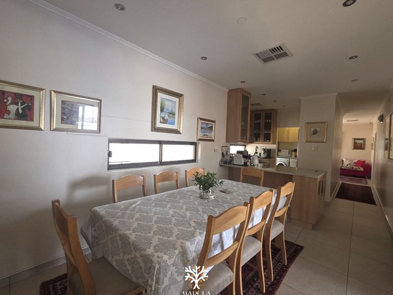 Open plan dining and kitchen area featuring tiled flooring, recessed lighting, and functional cabinetry with granite countertops.