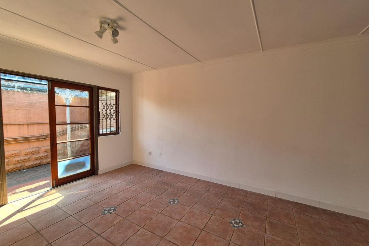 An empty living room featuring tiled flooring and a sliding glass door providing access to the exterior area.