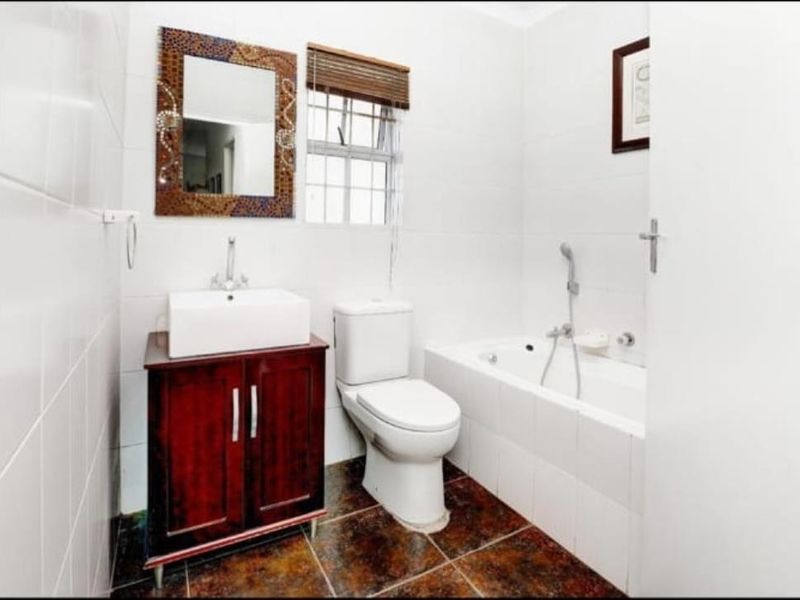 A functional bathroom featuring a vessel sink with vanity, a standard toilet, and a bathtub with a handheld shower mixer.