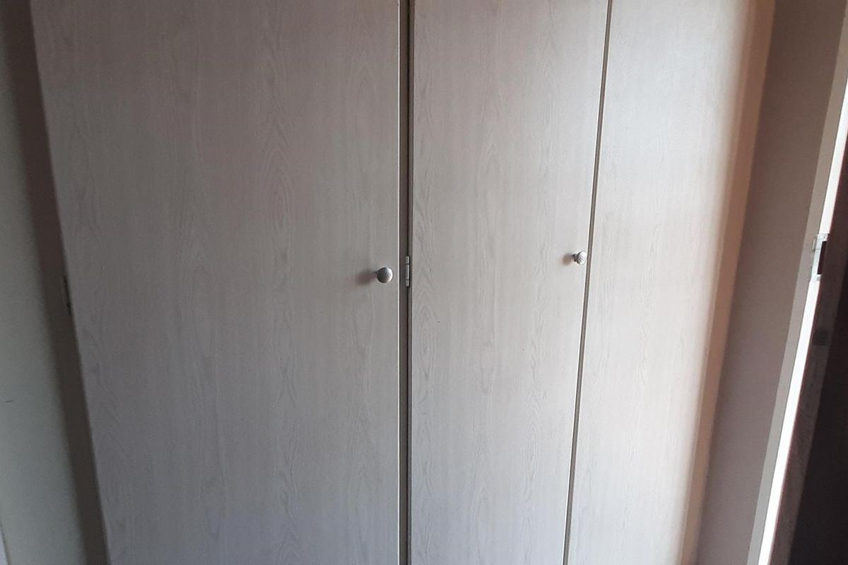 A view of built-in bedroom cupboards with light wood-grain finish doors.