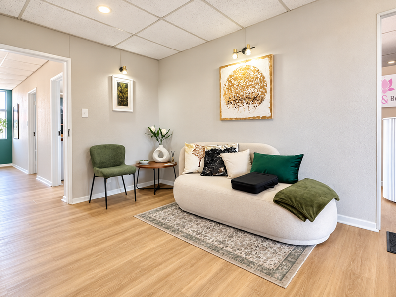 A bright and welcoming reception area featuring modern laminate flooring, a suspended ceiling, and neutral wall tones, providing a professional entry space.
