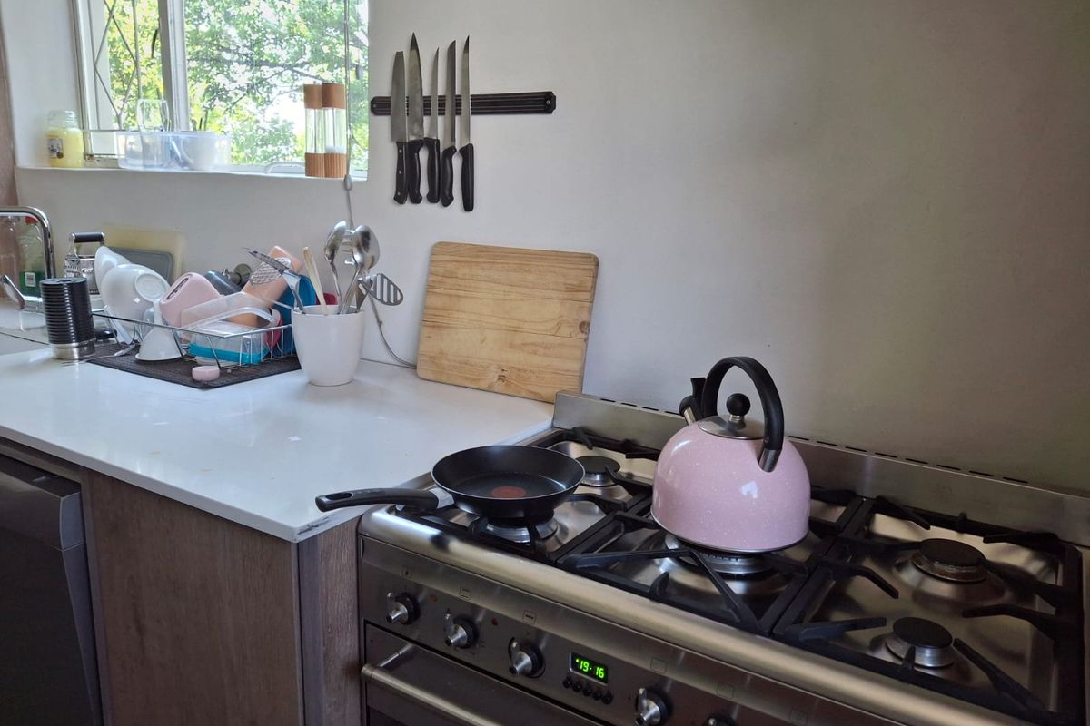 A functional kitchen area featuring a stainless steel gas stove and oven, stone-look countertops, and a wall-mounted magnetic knife rack.