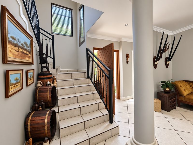Welcoming entrance hall featuring tiled flooring, a central structural column, and a tiled staircase with decorative wrought iron balustrades.