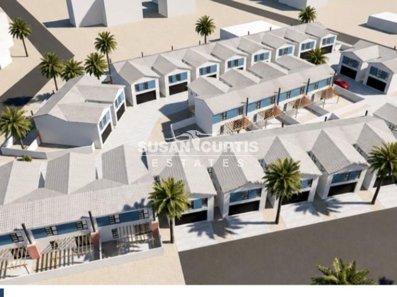An aerial perspective of a modern townhouse development featuring multiple units with pitched roofs, integrated garages, and paved outdoor areas.