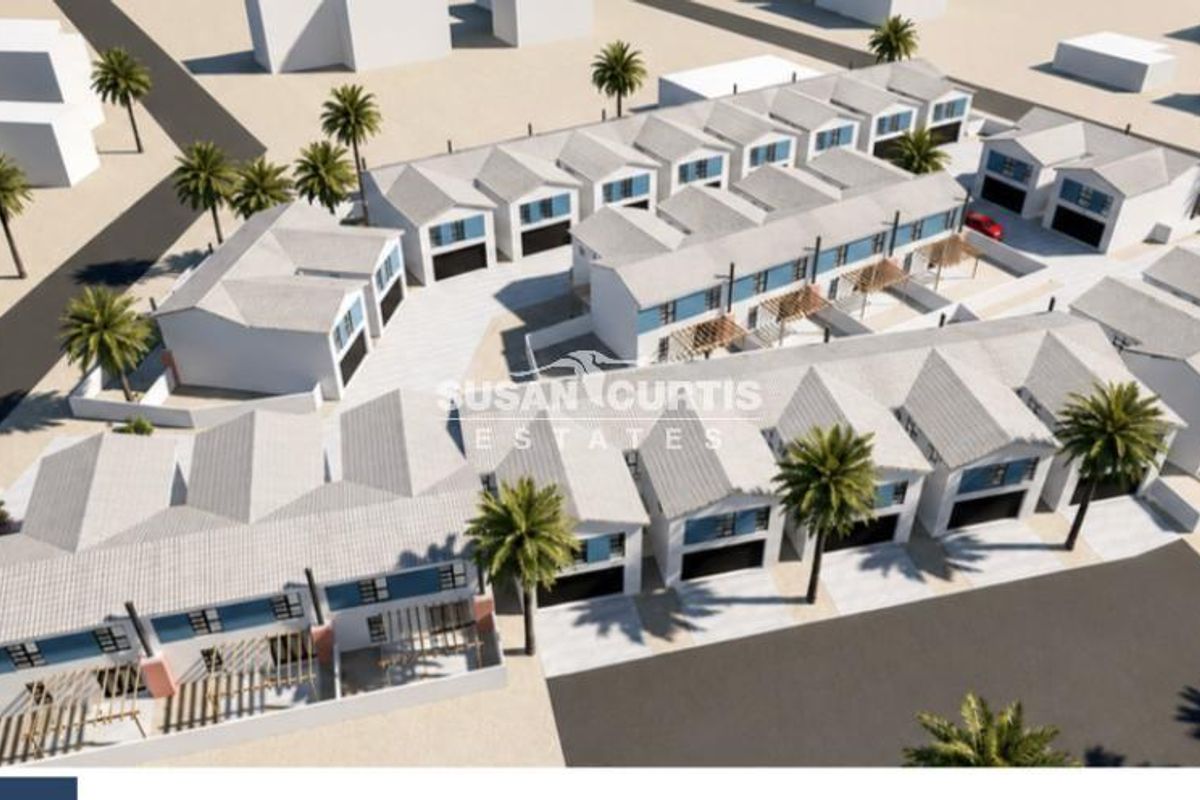 An aerial perspective of a modern townhouse development featuring multiple units with pitched roofs, integrated garages, and paved outdoor areas.