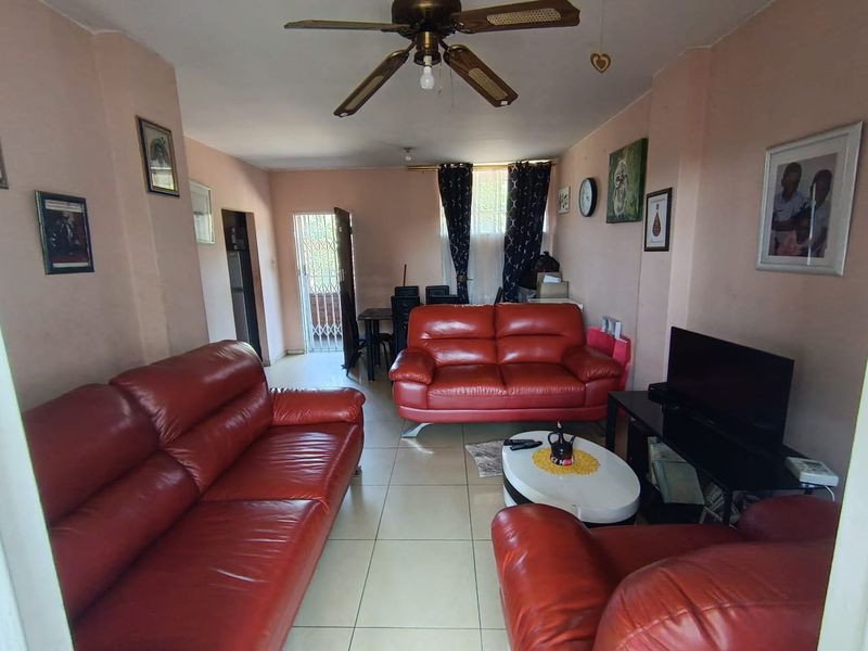 A living room featuring tiled flooring and a ceiling fan, with access to an exterior area through a security gate.