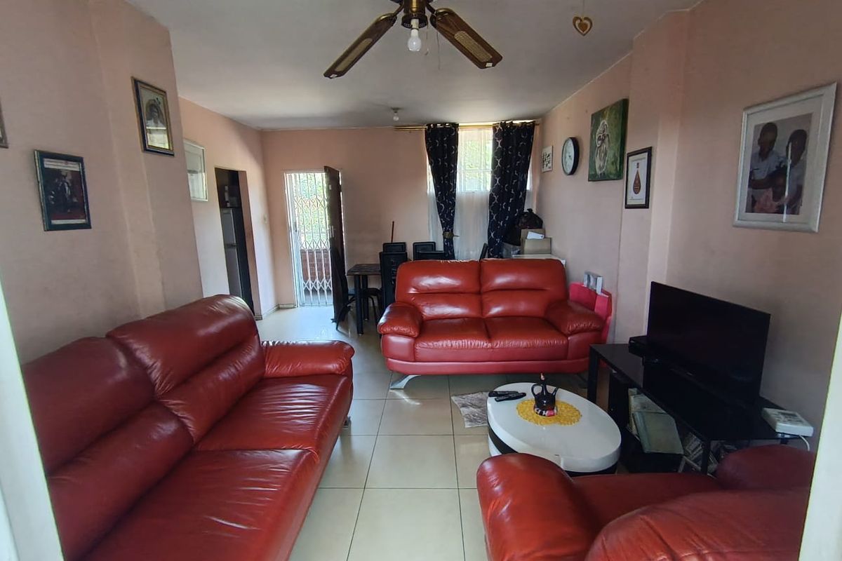 A living room featuring tiled flooring and a ceiling fan, with access to an exterior area through a security gate.