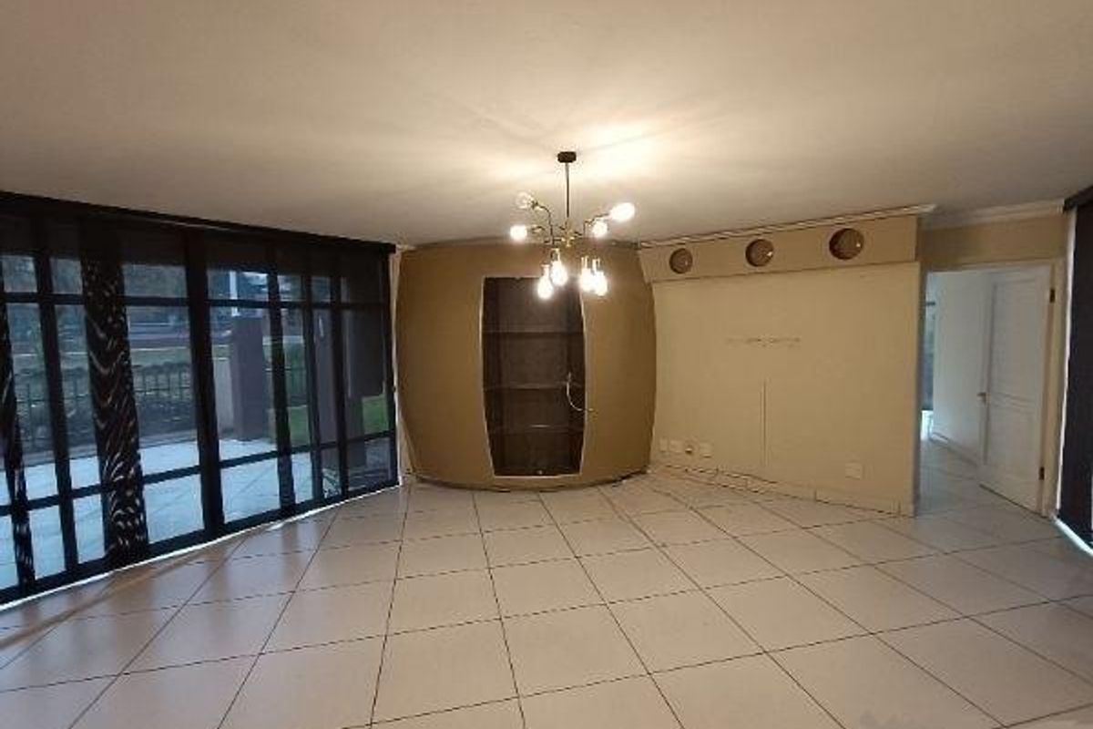 Spacious living area featuring large glass sliding doors, tiled flooring, and a unique built-in display cabinet with integrated lighting.