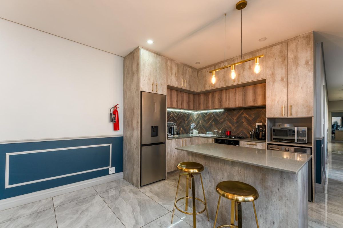 Modern kitchen featuring wood-look cabinetry, stone countertops, a breakfast bar, herringbone tile backsplash, and integrated appliances.