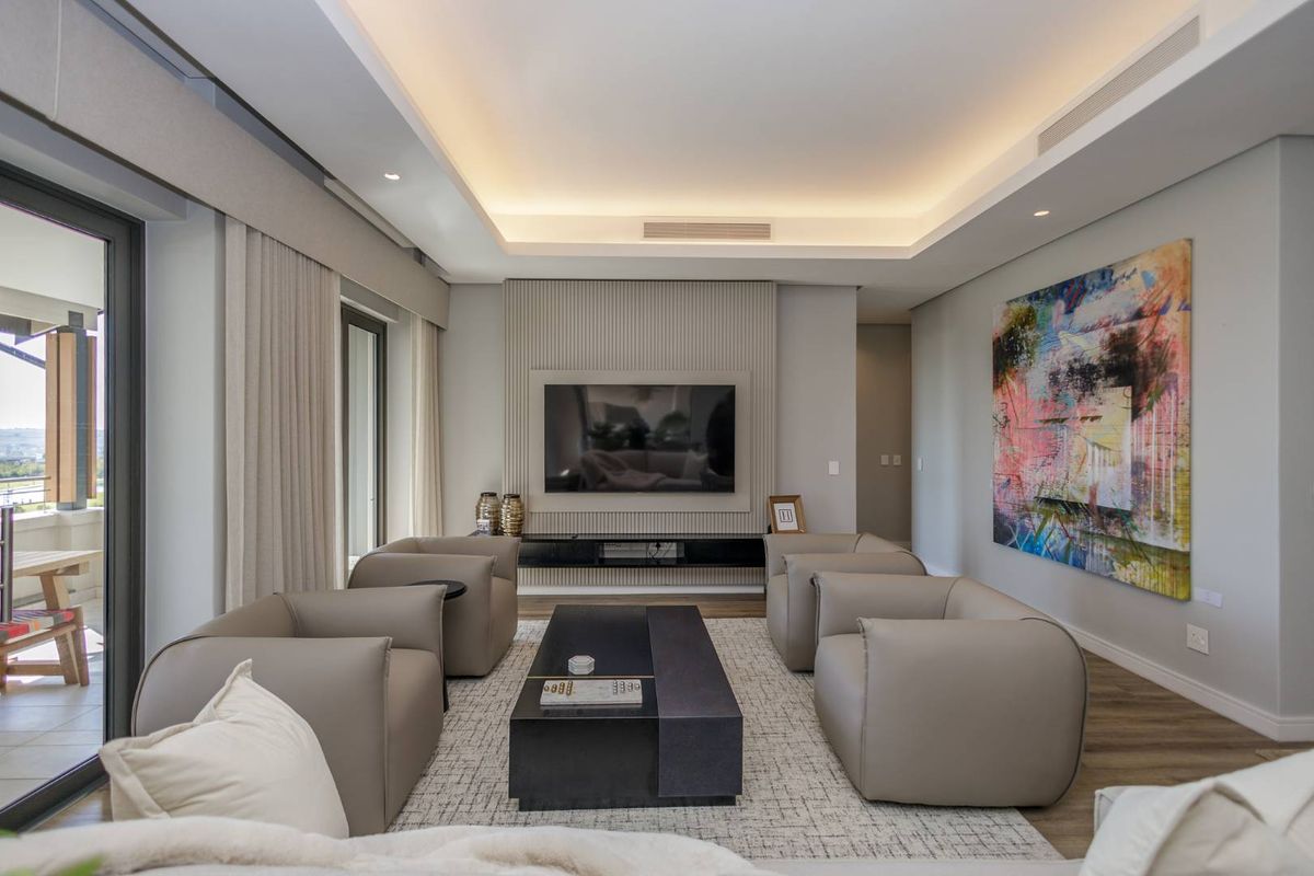 Modern living room featuring a recessed ceiling with integrated cove lighting, a textured feature wall with built-in media console, and large sliding doors to balcony.