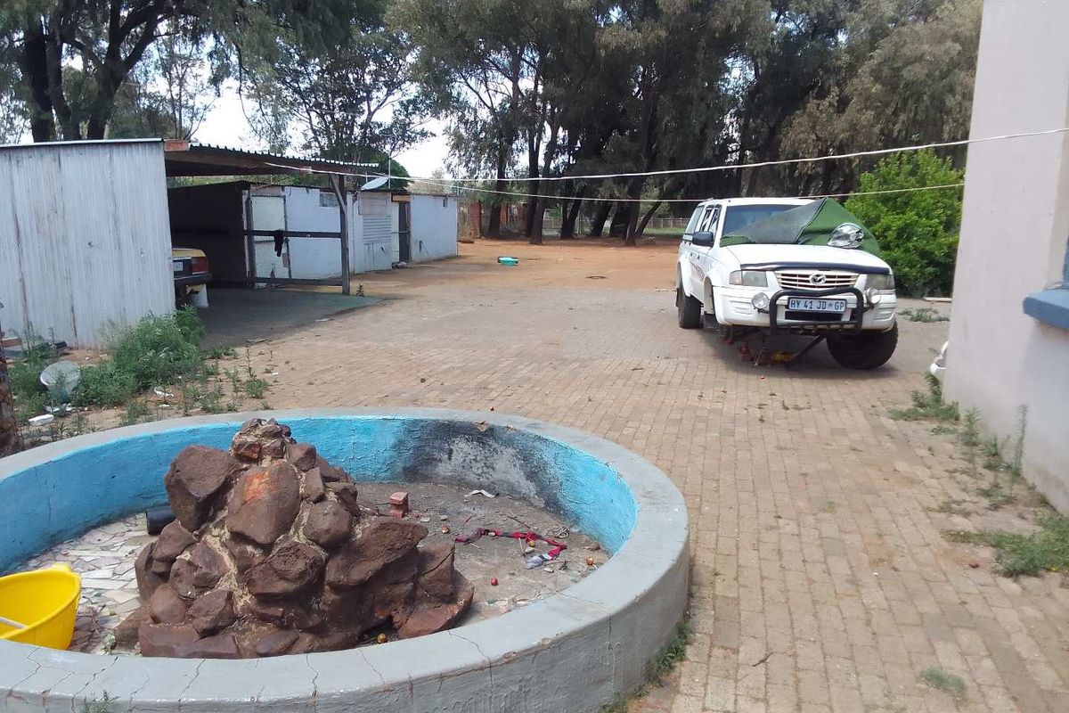 Outdoor area featuring a paved courtyard, a decorative stone fountain, and a covered storage or utility structure on a small holding property.