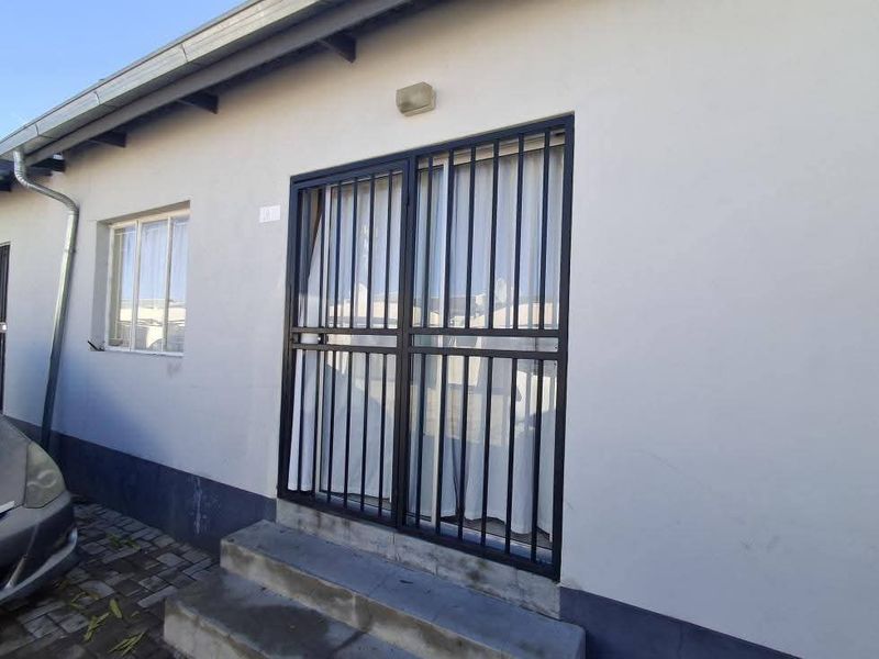 Exterior view of the property featuring a security gate, concrete entrance steps, and functional downpipe drainage system.