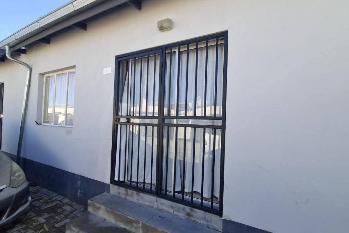 Exterior view of the property featuring a security gate, concrete entrance steps, and functional downpipe drainage system.