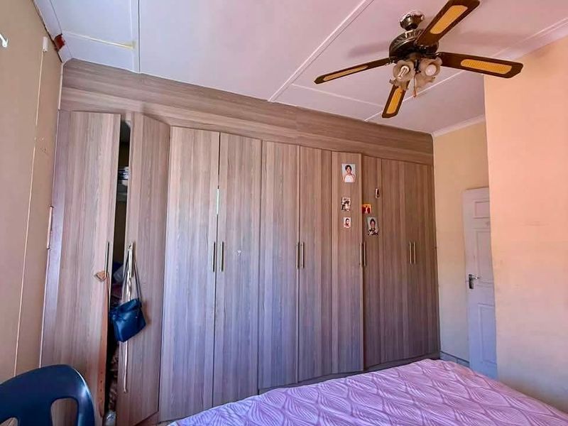 Bedroom featuring extensive built-in wooden cupboards and a ceiling fan.