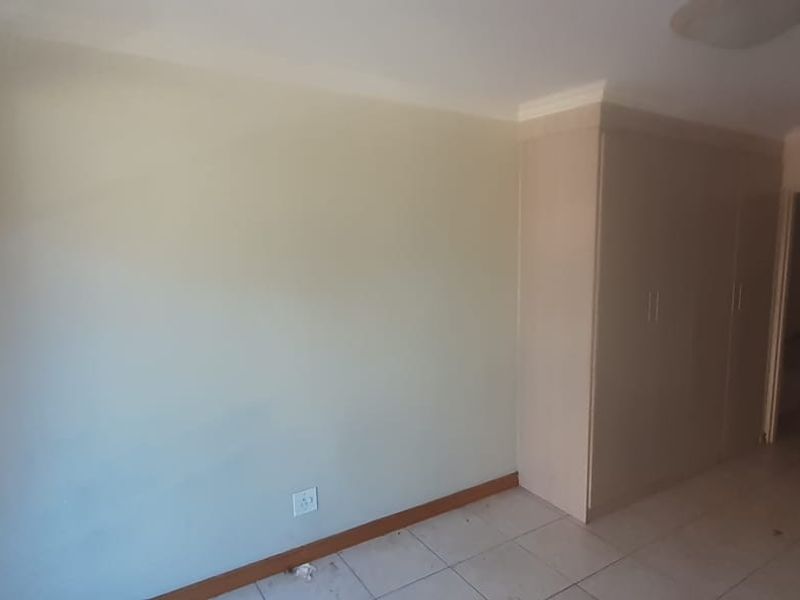An empty bedroom featuring built-in cupboards, tiled flooring, and neutral wall finishes, providing a blank canvas for personalization.