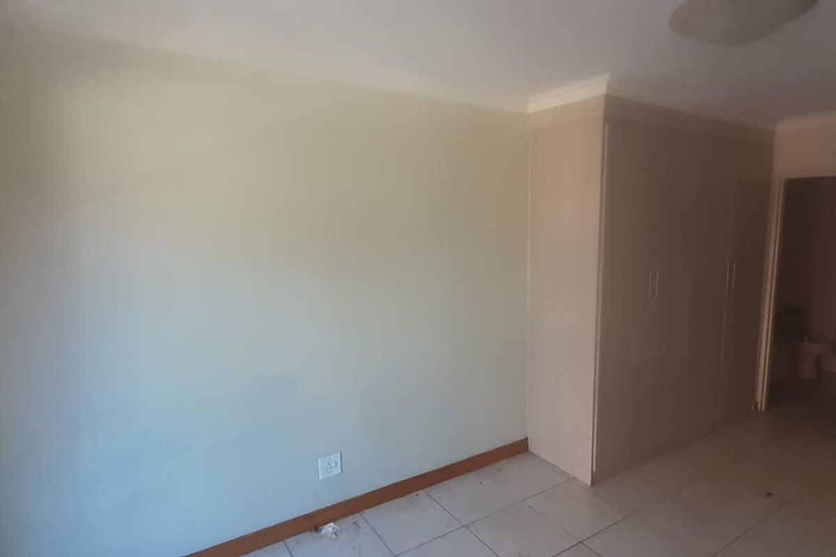 An empty bedroom featuring built-in cupboards, tiled flooring, and neutral wall finishes, providing a blank canvas for personalization.