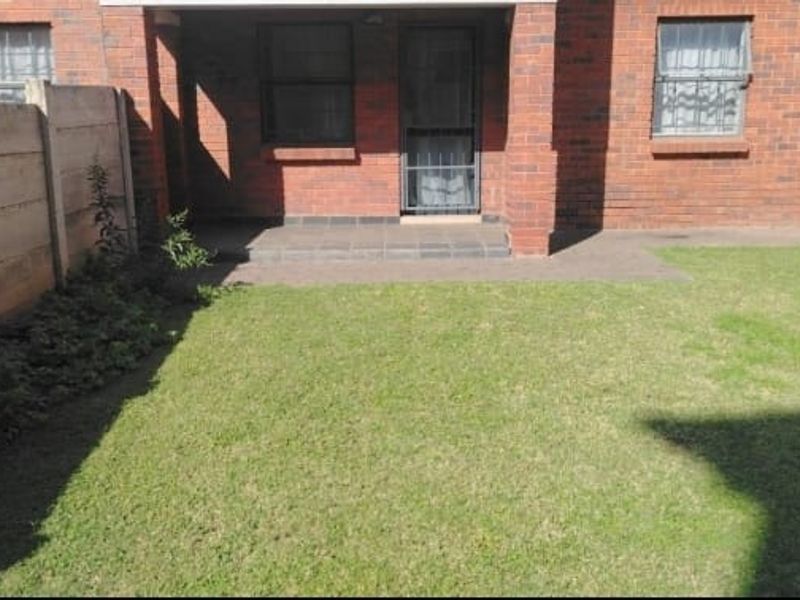 A private rear garden featuring a small concrete patio, brick facade, and precast concrete boundary walls.