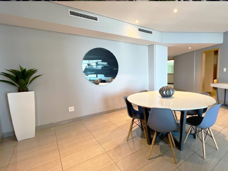 A modern dining area featuring neutral tiled flooring, recessed downlights, and integrated ducted air conditioning, creating a clean and functional living space.