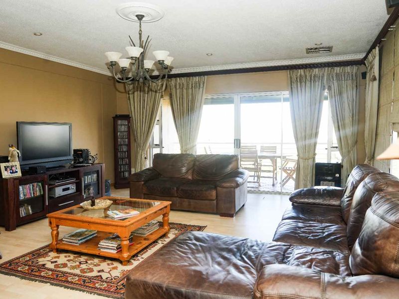 Spacious living room featuring laminate flooring, decorative ceiling rose, and large sliding glass doors providing access to an outdoor patio area.
