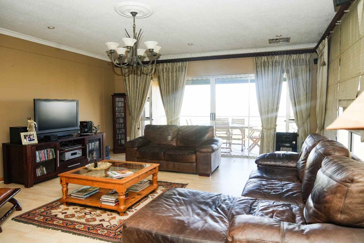 Spacious living room featuring laminate flooring, decorative ceiling rose, and large sliding glass doors providing access to an outdoor patio area.