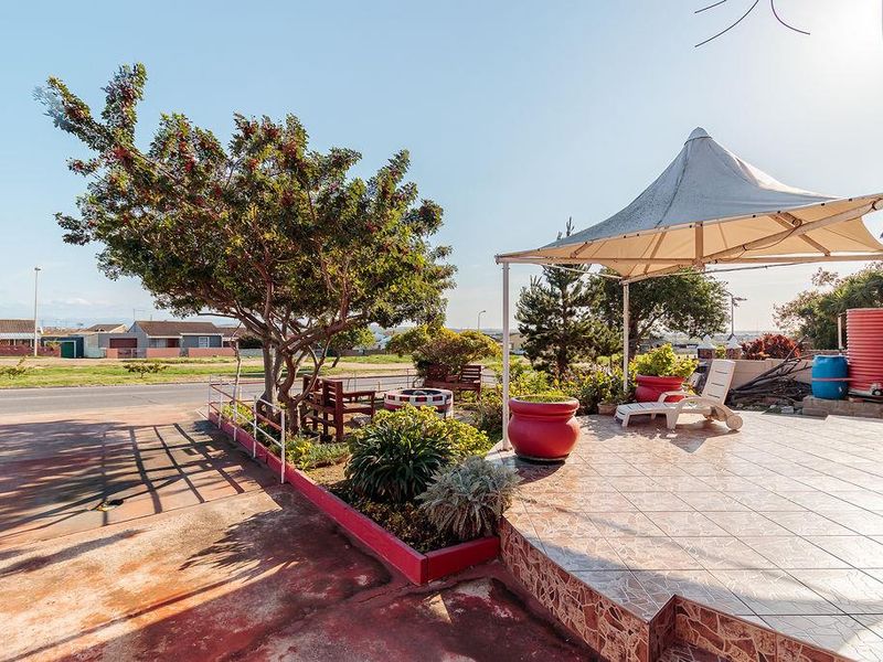 Outdoor patio area featuring a tiled surface, shade sail structure, and raised garden beds, providing a functional space for outdoor relaxation.