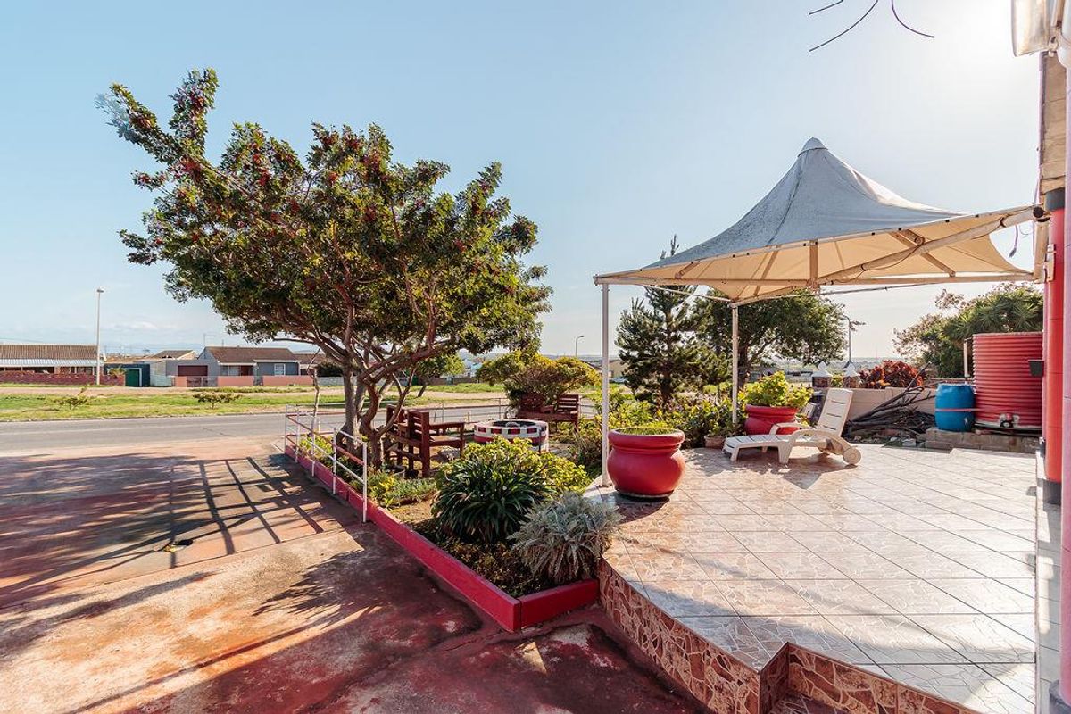 Outdoor patio area featuring a tiled surface, shade sail structure, and raised garden beds, providing a functional space for outdoor relaxation.