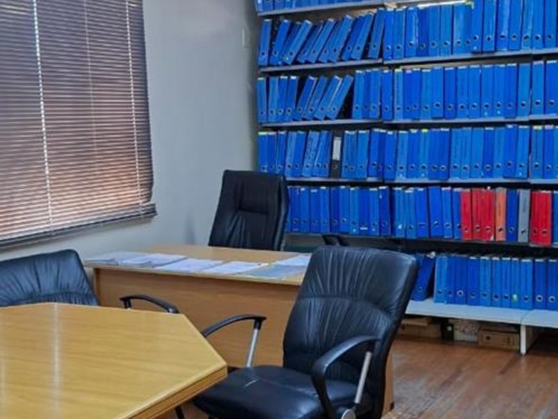 Functional office space featuring timber flooring, built-in storage shelving, and venetian blinds, providing a practical workspace environment.