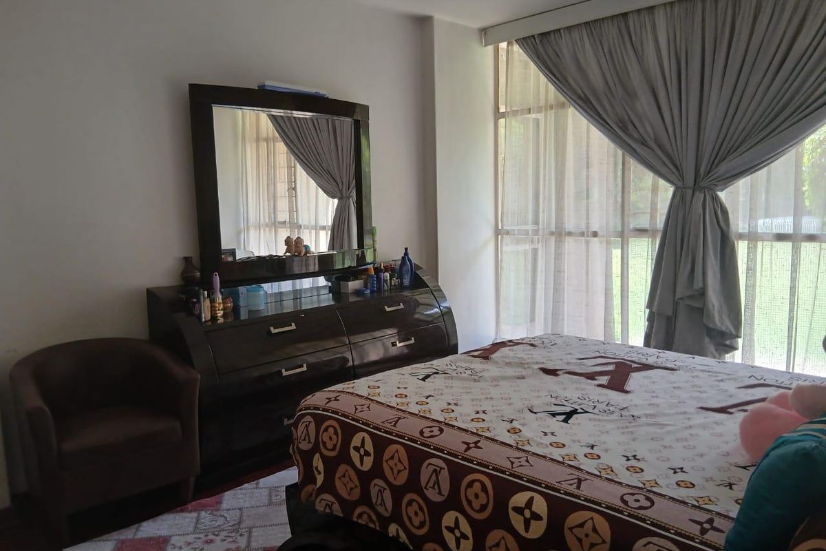 A bedroom featuring a large window with curtains, providing natural light and a view of the exterior.