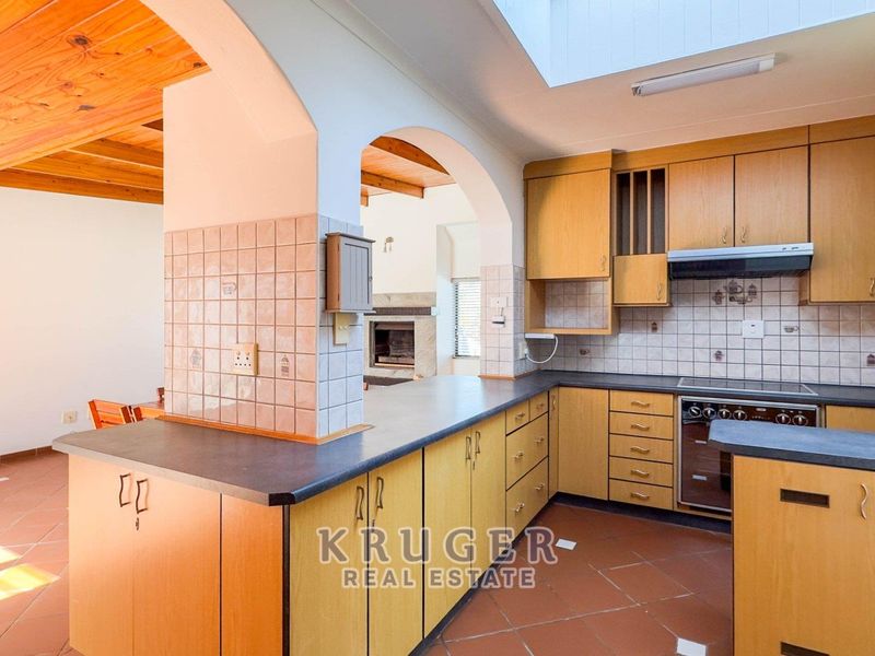 A functional kitchen featuring laminate cabinetry, built-in appliances, and a skylight, opening into an adjacent living area through a classic archway.