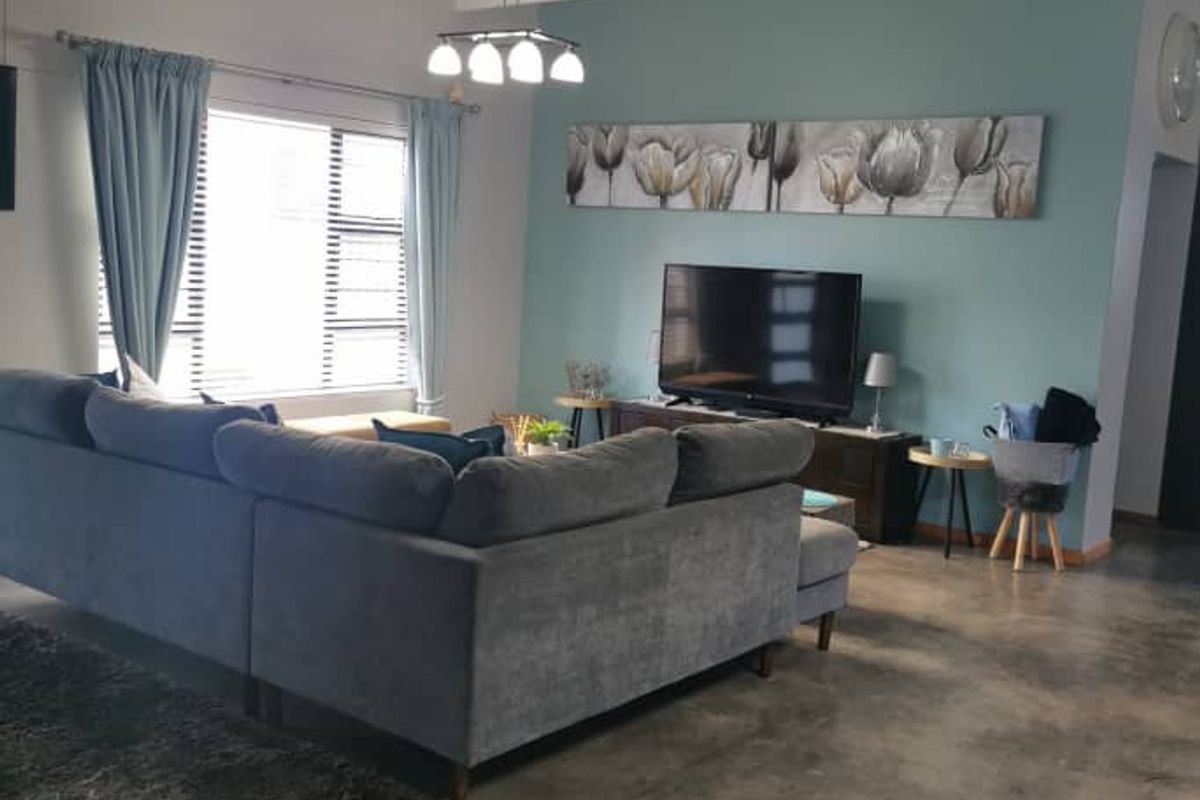 Spacious living area featuring high vaulted ceilings with exposed white trusses and polished concrete flooring, creating a modern and airy atmosphere.