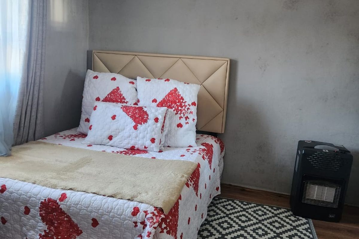 A bedroom featuring laminate flooring and a coved ceiling, currently requiring cosmetic updates to the wall finishes.