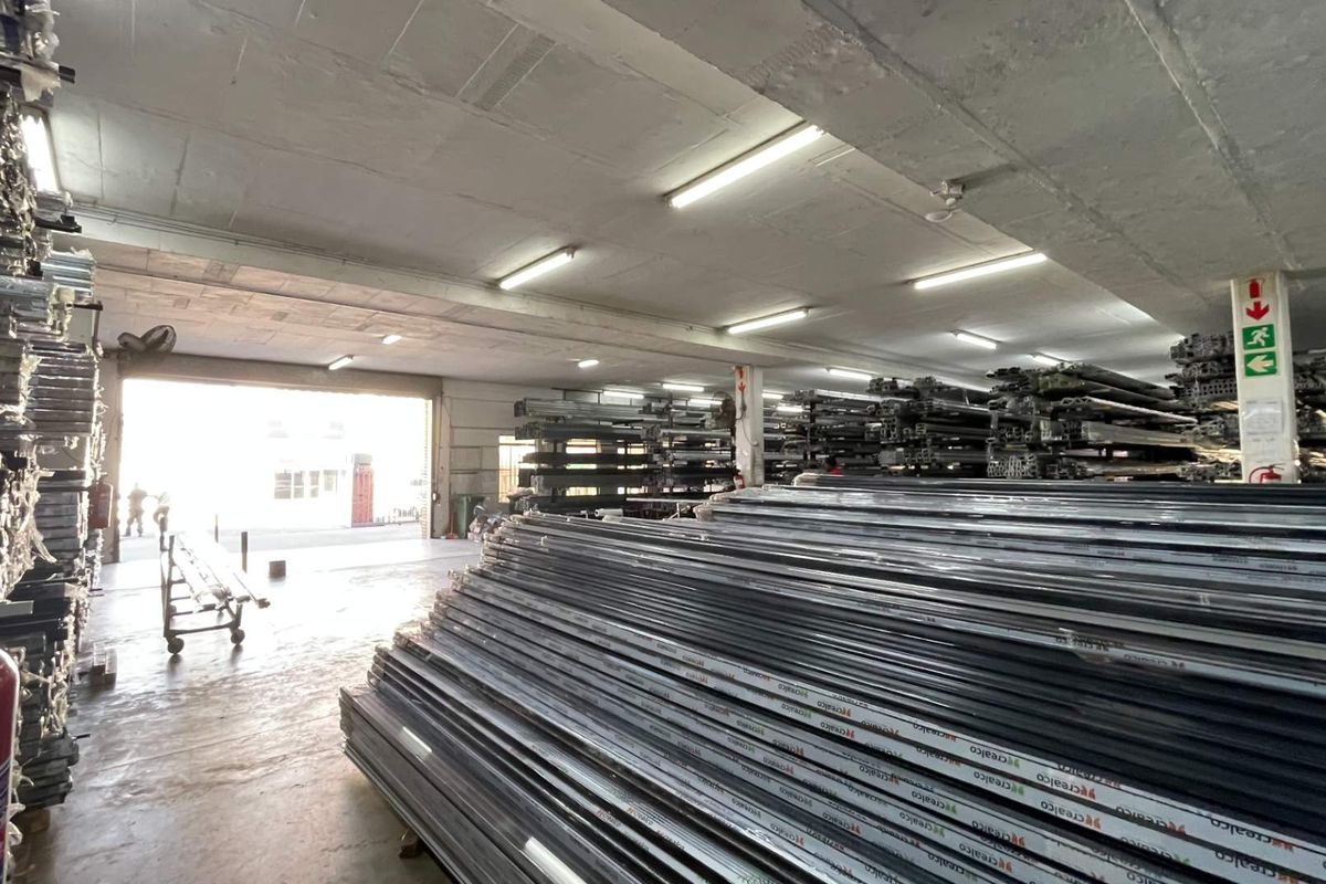A functional industrial utility or warehouse space featuring exposed concrete ceilings, fluorescent lighting, and a large roller door for loading access.