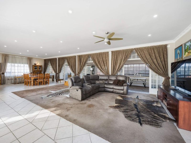 Spacious open-plan living and dining area featuring tiled floors, recessed lighting, and multiple sets of french doors leading to the exterior.
