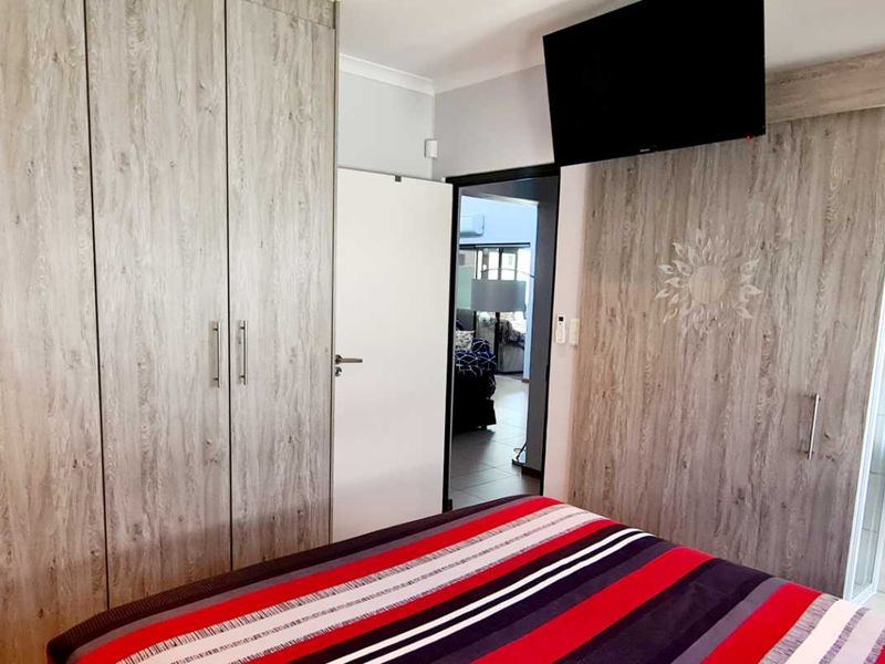 A bedroom featuring extensive built-in cupboards and a sliding door leading to an en-suite bathroom with a vanity basin and toilet.