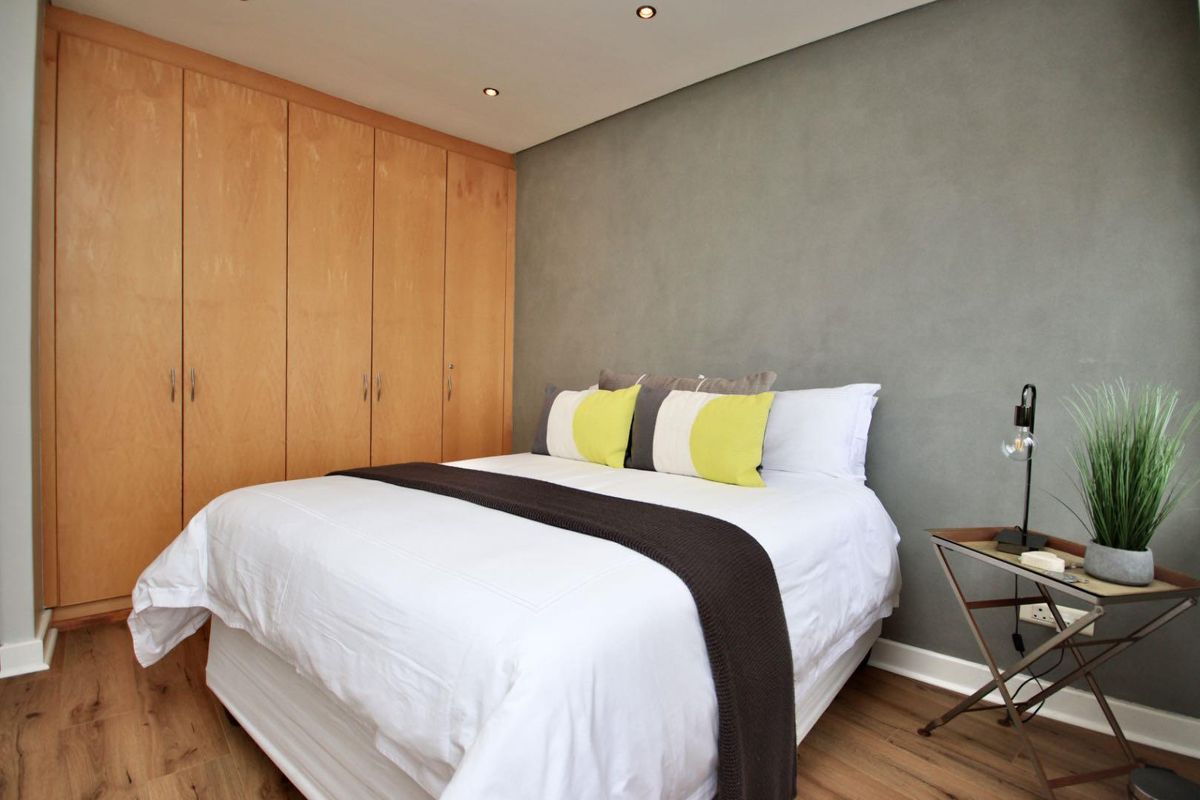 A well-maintained bedroom featuring built-in wooden cabinetry, recessed ceiling lighting, and wood-look flooring.