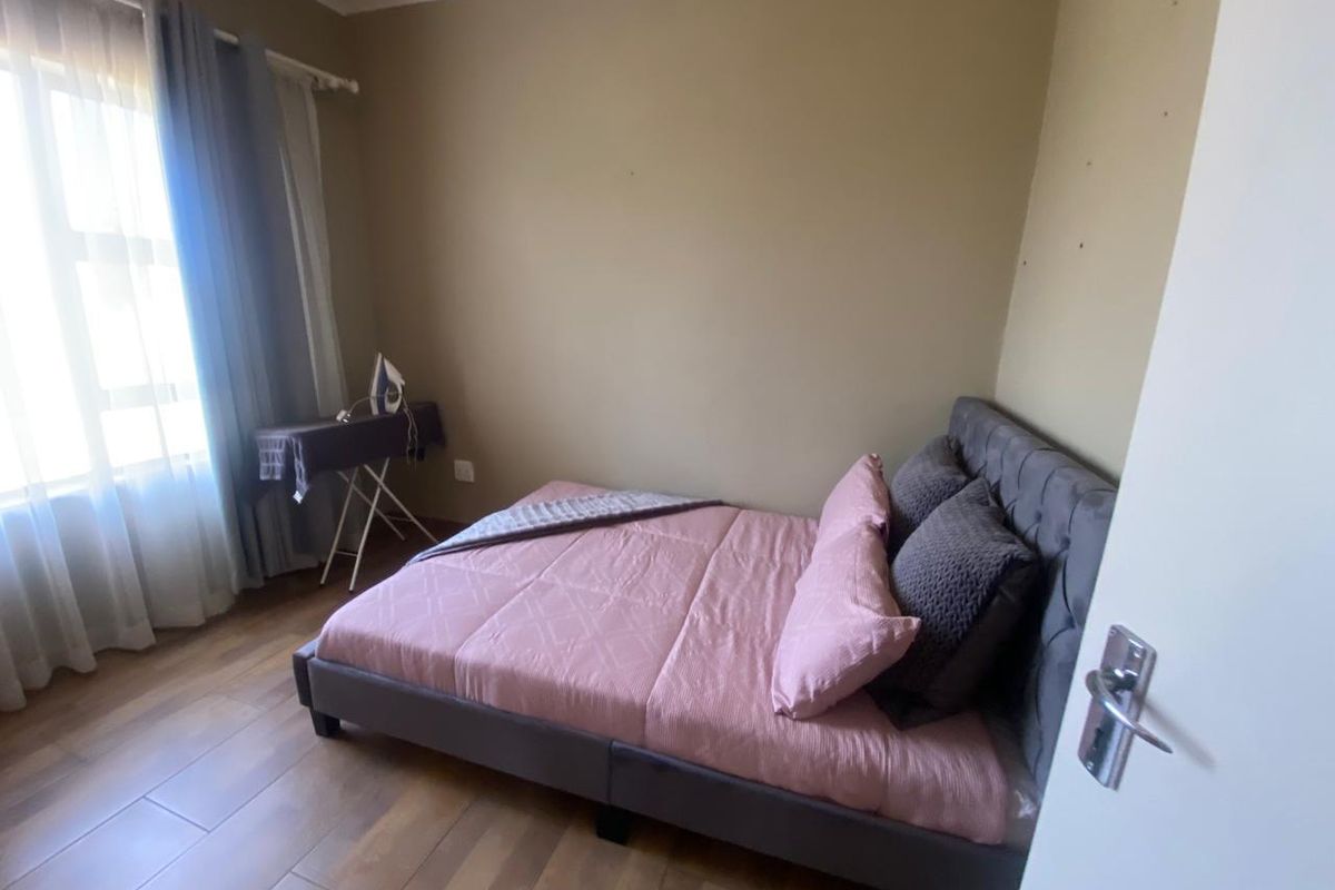 A bedroom featuring wood-look tiled flooring and neutral wall tones, providing a functional and comfortable sleeping space.