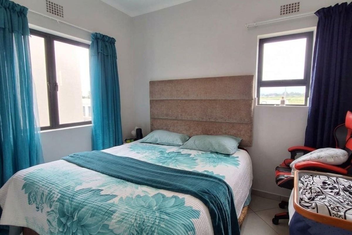 A functional bedroom featuring tiled flooring, neutral wall finishes, and aluminium-framed windows providing natural light.