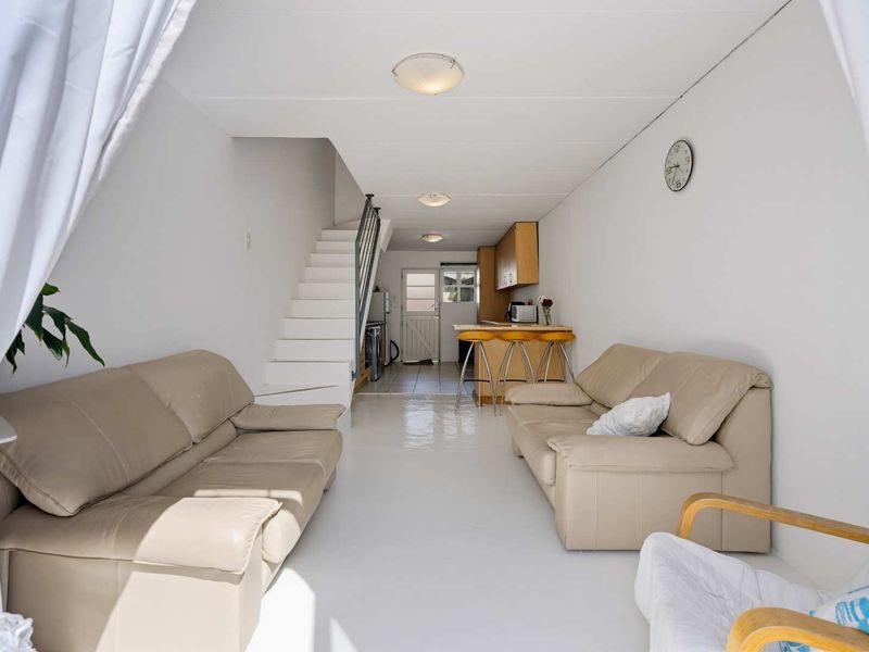 Open plan living area featuring a staircase, kitchen with breakfast bar, and neutral tiled flooring, providing a functional and connected layout.
