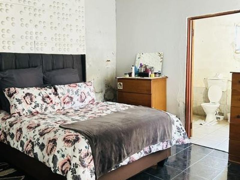 Bedroom featuring dark tiled flooring, textured wall accents, and direct access to an en-suite bathroom.