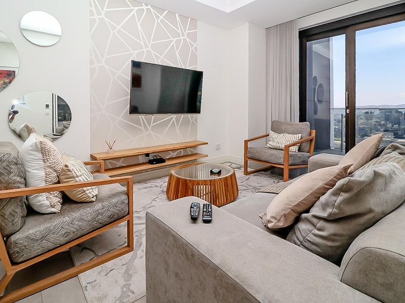 Modern living room featuring a floating timber media shelf, tiled flooring, and large sliding glass doors leading to a balcony with city views.