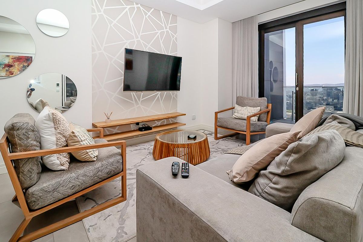 Modern living room featuring a floating timber media shelf, tiled flooring, and large sliding glass doors leading to a balcony with city views.