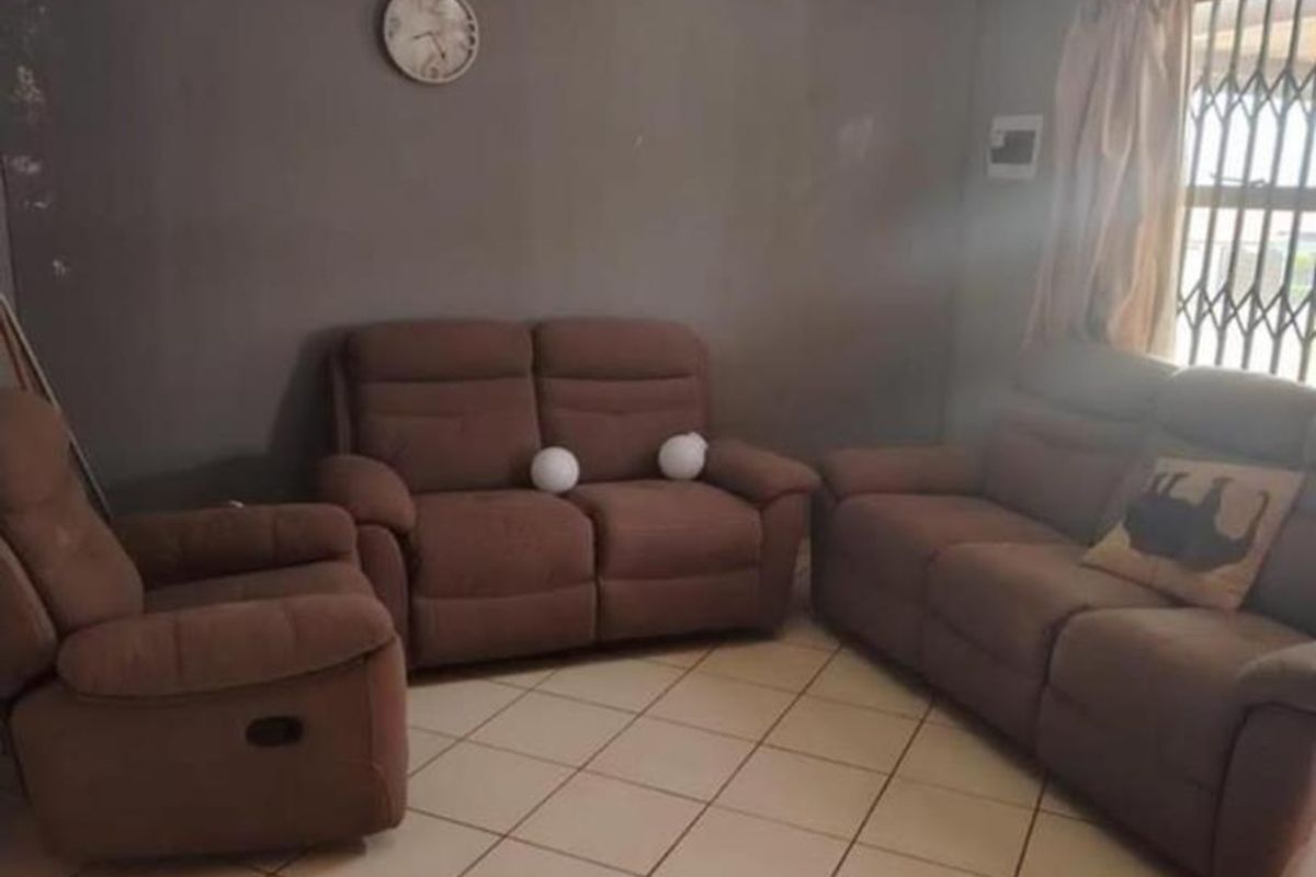 A living room featuring tiled flooring and a window with a security gate, providing a functional space for relaxation.