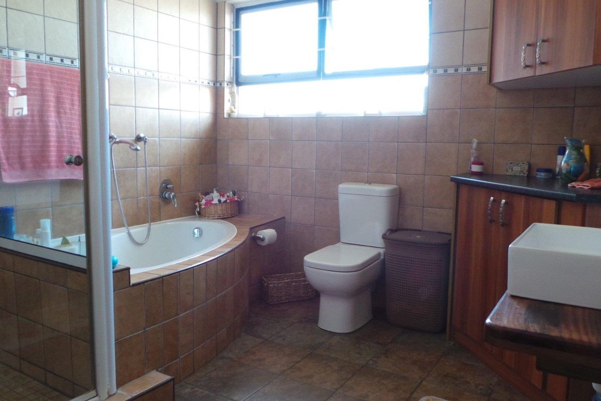 A functional bathroom featuring a built-in bathtub, a separate shower enclosure, a toilet, and a vanity unit with storage cabinetry.